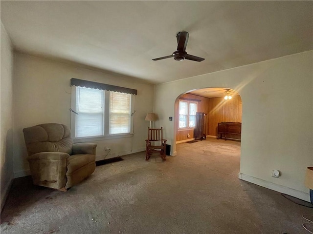 unfurnished room with baseboards, arched walkways, and a ceiling fan