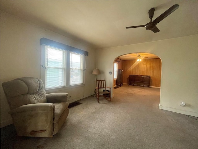 living area with carpet, arched walkways, and a ceiling fan