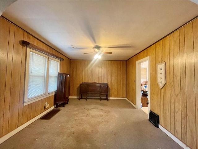 sitting room featuring wood walls, ceiling fan, and baseboards