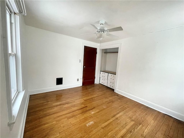 unfurnished bedroom with a closet, wood-type flooring, ceiling fan, and baseboards