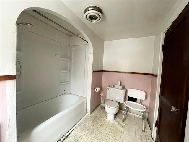 bathroom featuring toilet, shower / tub combination, and baseboards