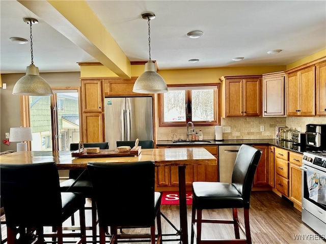 kitchen featuring stainless steel appliances, backsplash, a sink, and dark wood finished floors