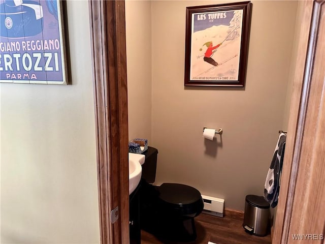 bathroom featuring baseboard heating, toilet, vanity, wood finished floors, and baseboards