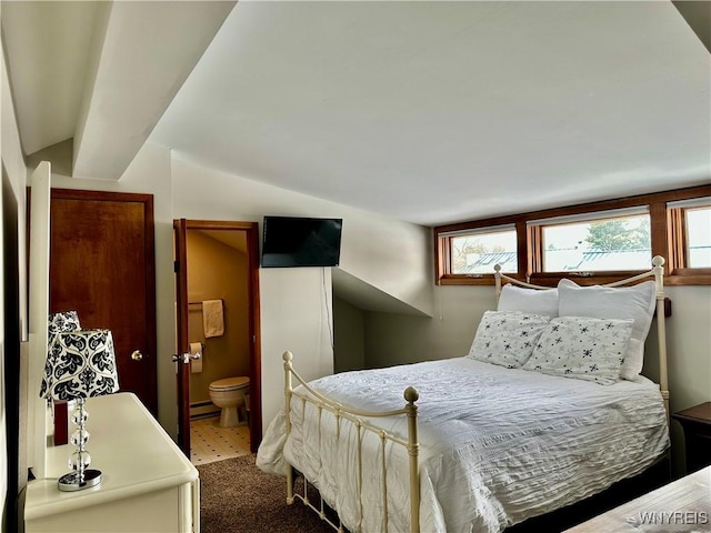 bedroom with lofted ceiling, ensuite bath, and a baseboard heating unit