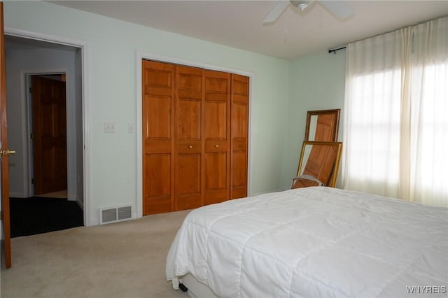 carpeted bedroom with ceiling fan, visible vents, and a closet