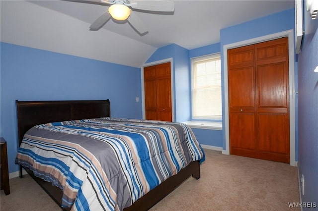 bedroom with lofted ceiling, ceiling fan, baseboards, carpet, and two closets