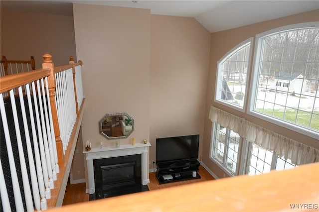 living area with plenty of natural light, high vaulted ceiling, baseboards, and a fireplace with flush hearth