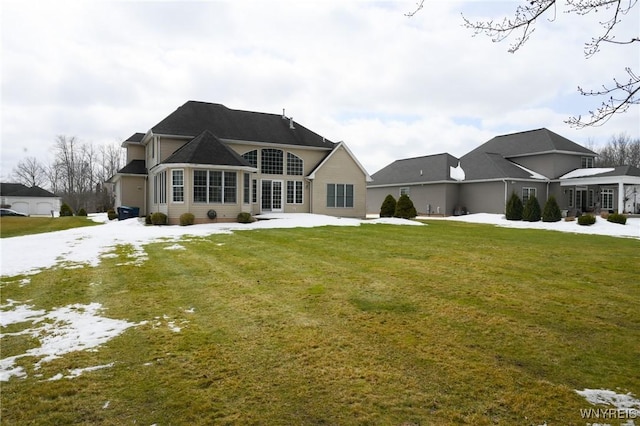 snow covered rear of property with a lawn and a patio area