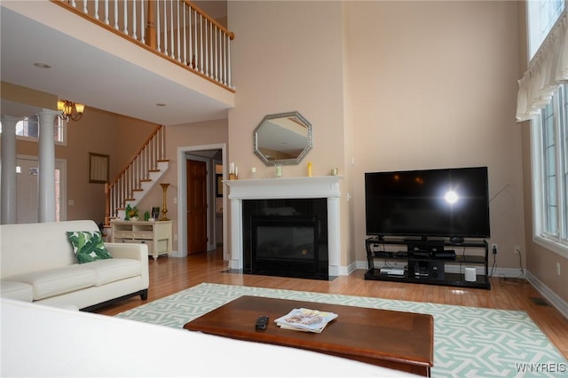 living room featuring stairs, a towering ceiling, baseboards, and wood finished floors