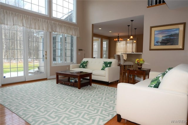 living area featuring a high ceiling, wood finished floors, and a notable chandelier