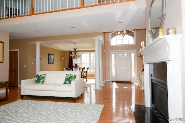 living area with a chandelier, a wealth of natural light, and ornate columns