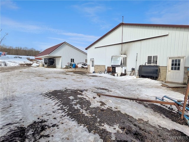 snow covered property with an outbuilding, a detached garage, and an outdoor structure