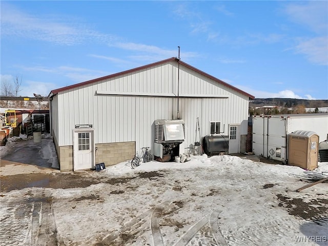 snow covered structure with heating fuel and an outbuilding