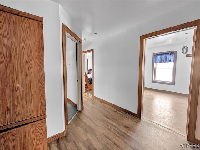 hallway with light wood-type flooring and baseboards