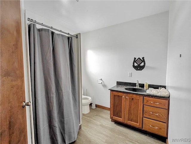 bathroom featuring toilet, wood finished floors, vanity, baseboards, and a shower with curtain