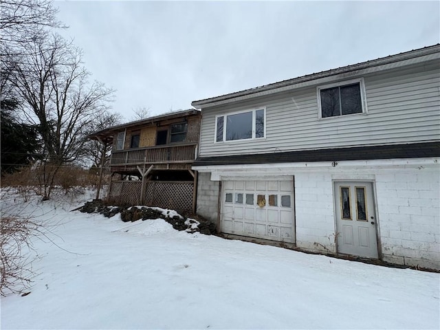 snow covered back of property with an attached garage