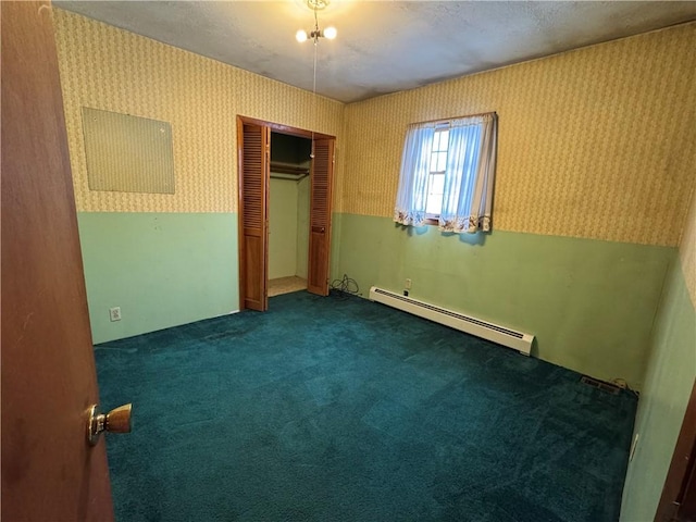 unfurnished bedroom featuring dark colored carpet, a closet, a baseboard radiator, and wallpapered walls