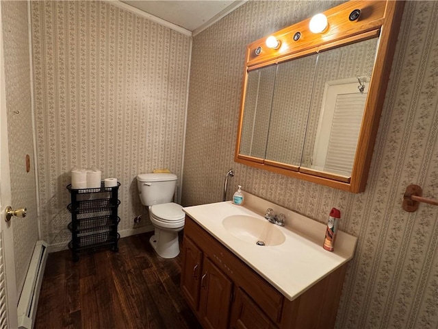 half bathroom featuring a baseboard radiator, wood finished floors, vanity, and wallpapered walls