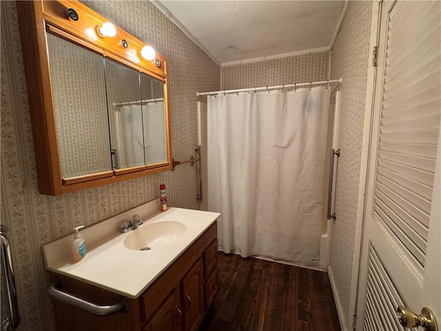 bathroom featuring wallpapered walls, shower / bath combination with curtain, wood finished floors, and vanity