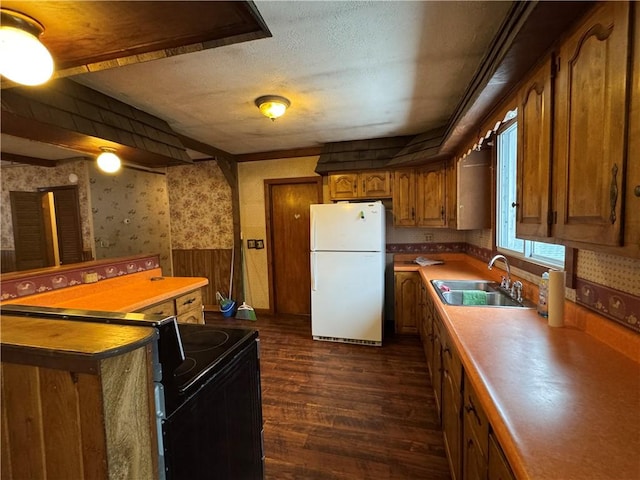 kitchen featuring a wainscoted wall, electric range, freestanding refrigerator, a sink, and wallpapered walls