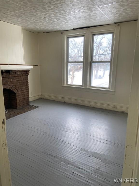 unfurnished living room featuring a fireplace, baseboards, and hardwood / wood-style flooring