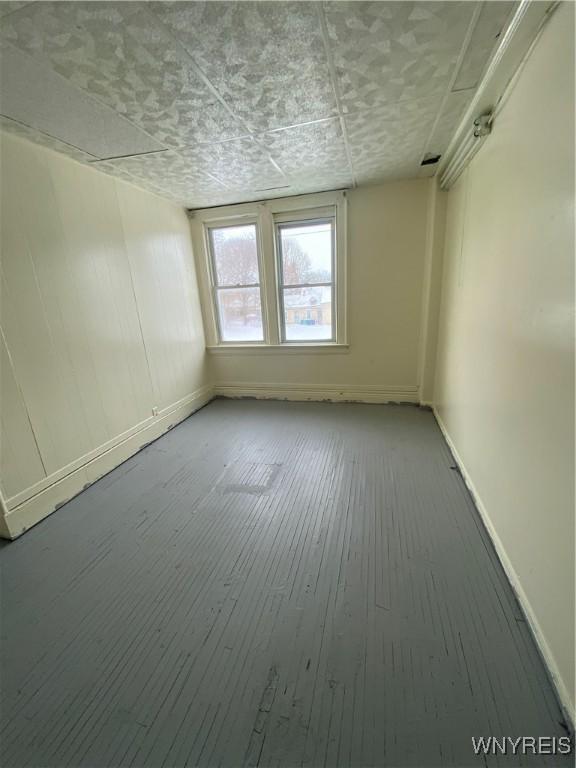 spare room with wood-type flooring and baseboards