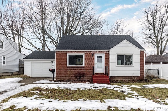 view of front facade with an attached garage, brick siding, a shingled roof, fence, and driveway