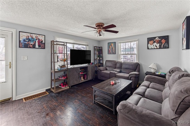 living room with baseboards, visible vents, a ceiling fan, wood finished floors, and a textured ceiling