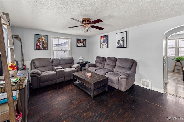 living area with arched walkways, hardwood / wood-style flooring, visible vents, baseboards, and a ceiling fan