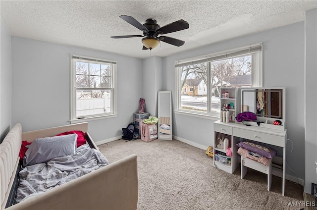 bedroom with carpet, a textured ceiling, baseboards, and a ceiling fan