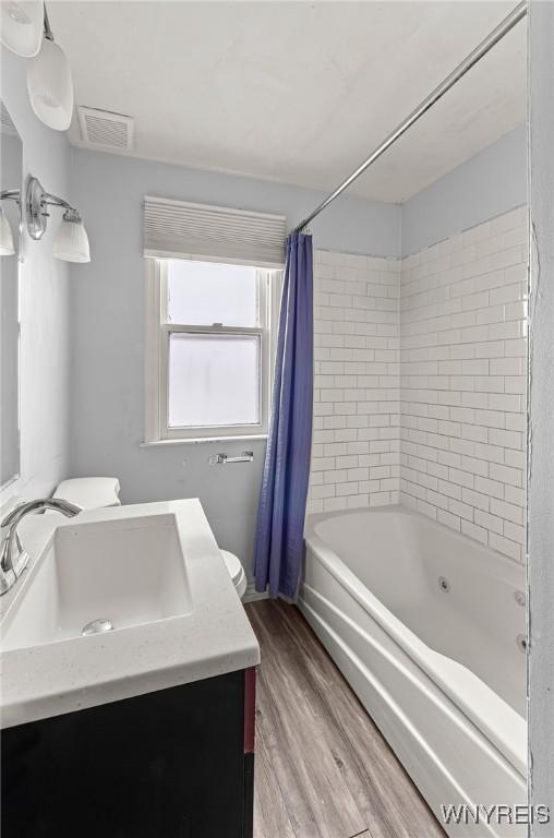 full bathroom featuring visible vents, shower / bathtub combination with curtain, vanity, and wood finished floors