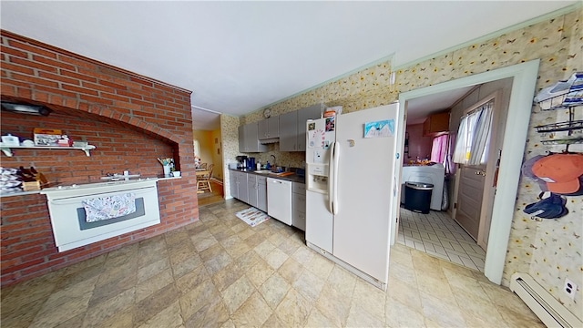 kitchen featuring white appliances, washer / dryer, a baseboard radiator, brick wall, and gray cabinetry