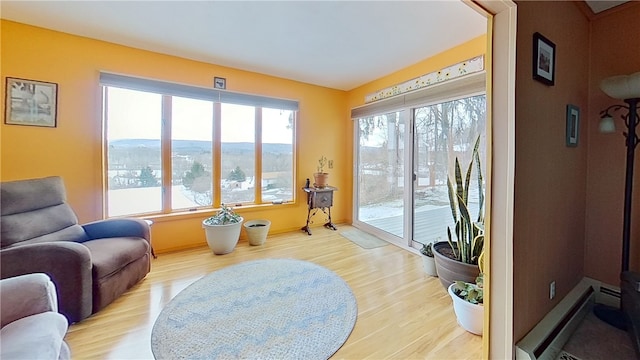 sitting room with a baseboard heating unit and wood finished floors