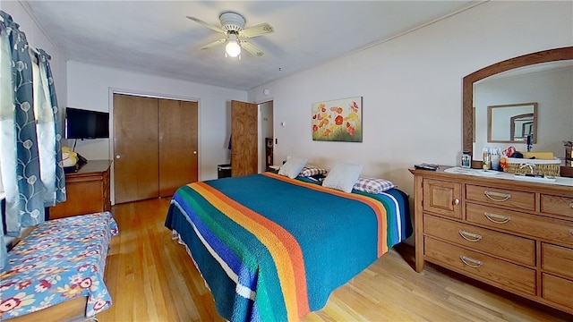 bedroom featuring light wood-style floors, arched walkways, a closet, and ceiling fan