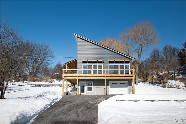 view of front facade featuring an attached garage, driveway, and a wooden deck