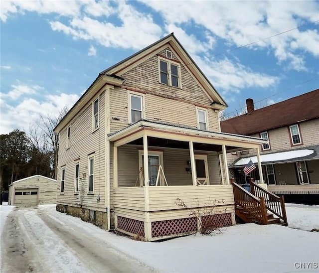 american foursquare style home featuring an outbuilding, covered porch, and a detached garage