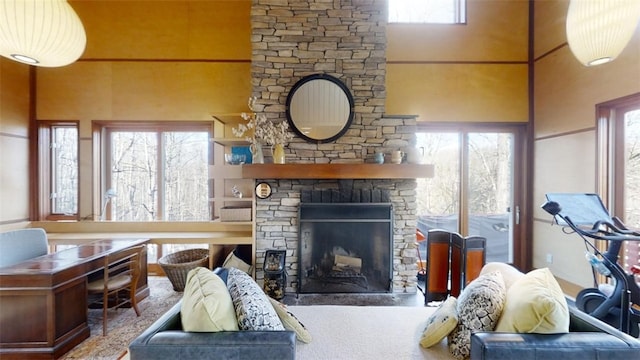 living area featuring a healthy amount of sunlight, a high ceiling, and a stone fireplace