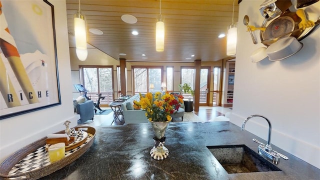 kitchen featuring open floor plan, dark countertops, a sink, and pendant lighting