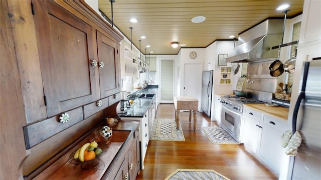 kitchen featuring wall chimney range hood, wood ceiling, appliances with stainless steel finishes, and wood finished floors