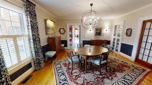 dining room featuring visible vents, wood finished floors, and ornamental molding