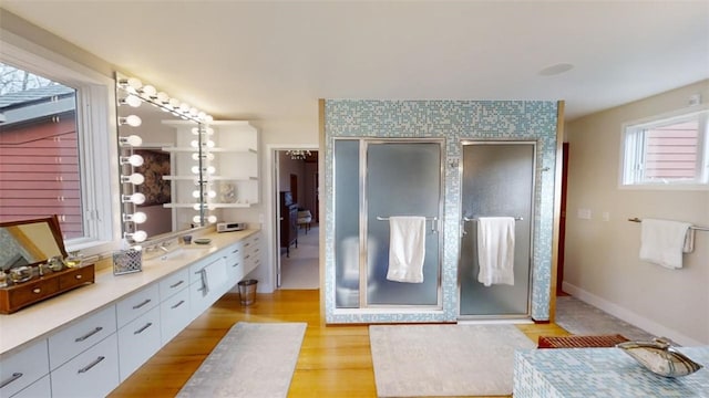 bathroom with a shower stall, baseboards, wood finished floors, and vanity