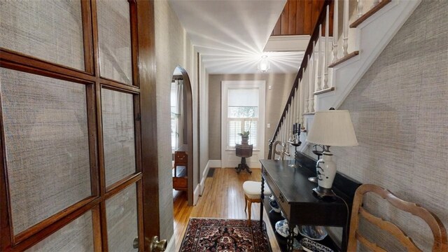 interior space with stairs, light wood-type flooring, and arched walkways