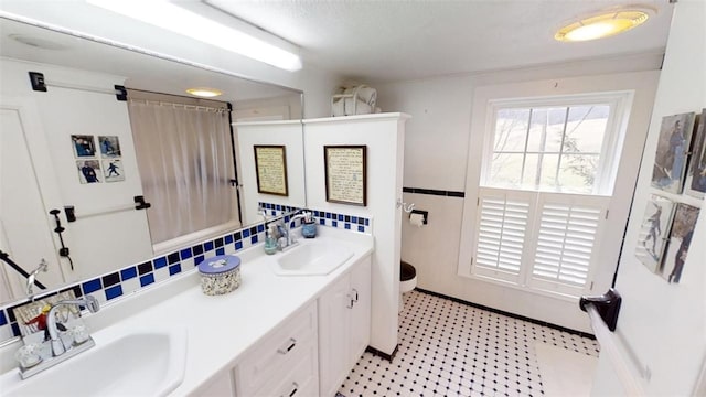 bathroom featuring tile patterned floors, a sink, tile walls, and double vanity