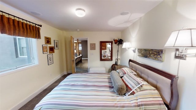 bedroom featuring baseboards and dark carpet