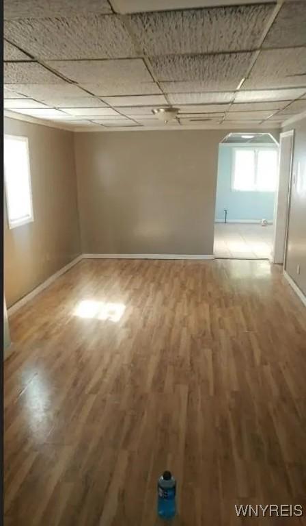 spare room with a paneled ceiling, baseboards, and wood finished floors