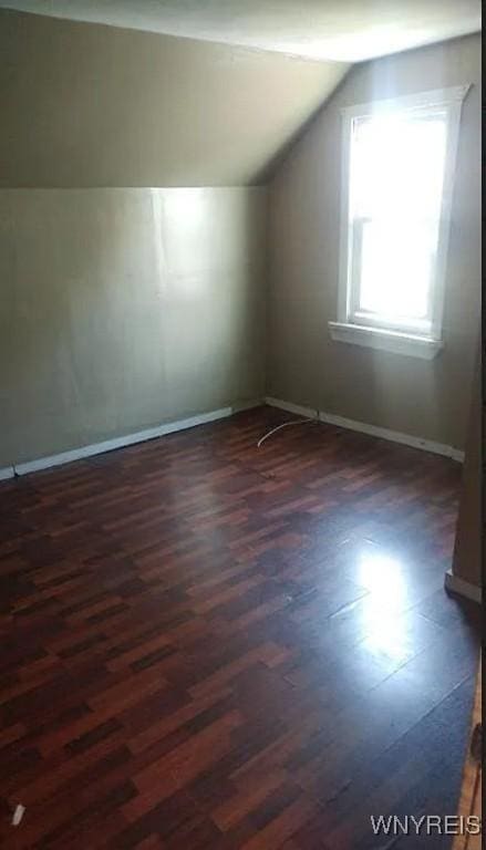 bonus room featuring vaulted ceiling, dark wood-style flooring, and baseboards