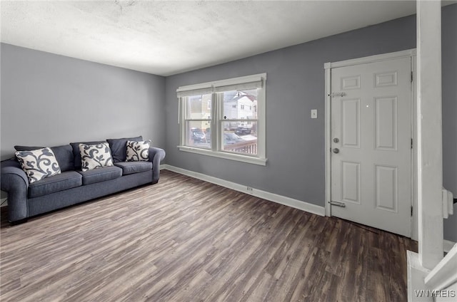 living room with a textured ceiling, wood finished floors, and baseboards