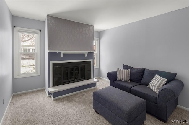 living room featuring a glass covered fireplace, carpet flooring, and baseboards