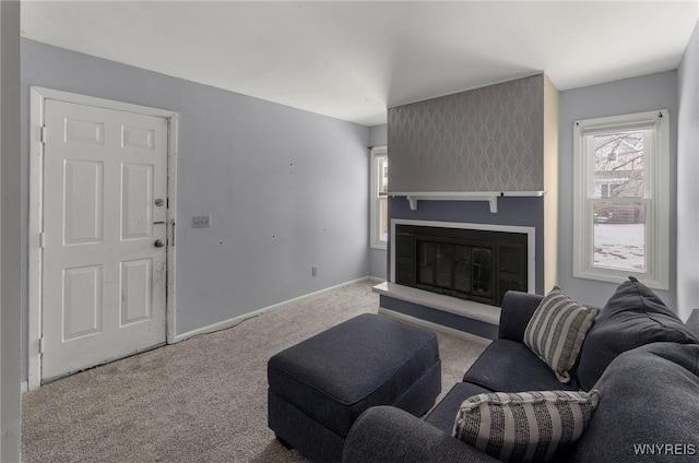 carpeted living room featuring a glass covered fireplace and baseboards