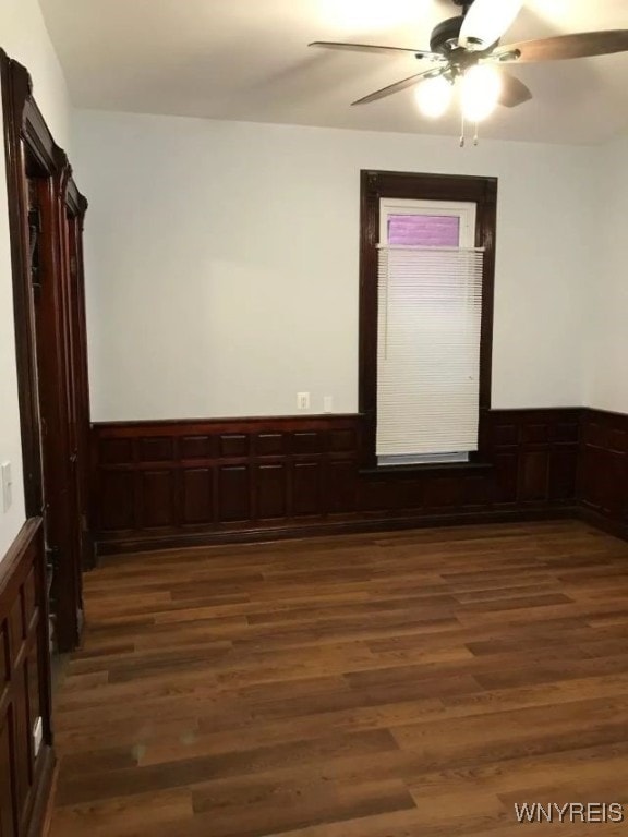 spare room with a wainscoted wall, ceiling fan, and wood finished floors